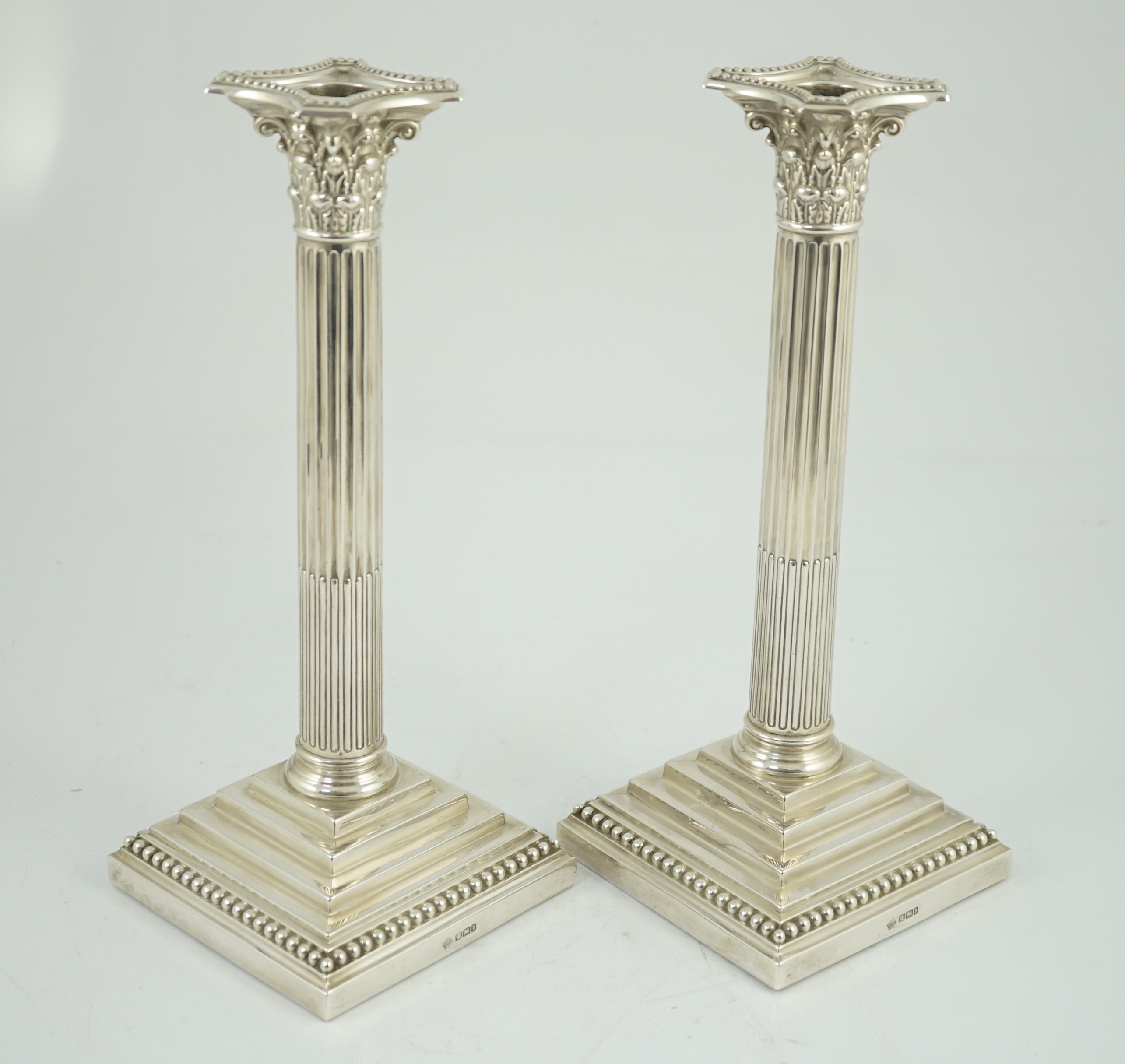 A pair of late Victorian silver Corinthian column candlesticks, by William Hutton & Sons